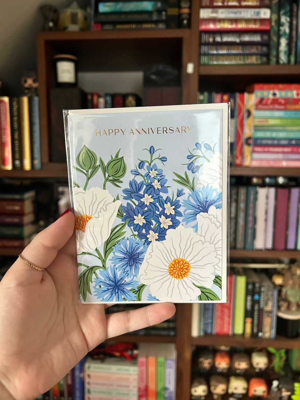 Floral anniversary greeting card featuring blue and white flowers on a soft blue background with the words "Happy Anniversary."