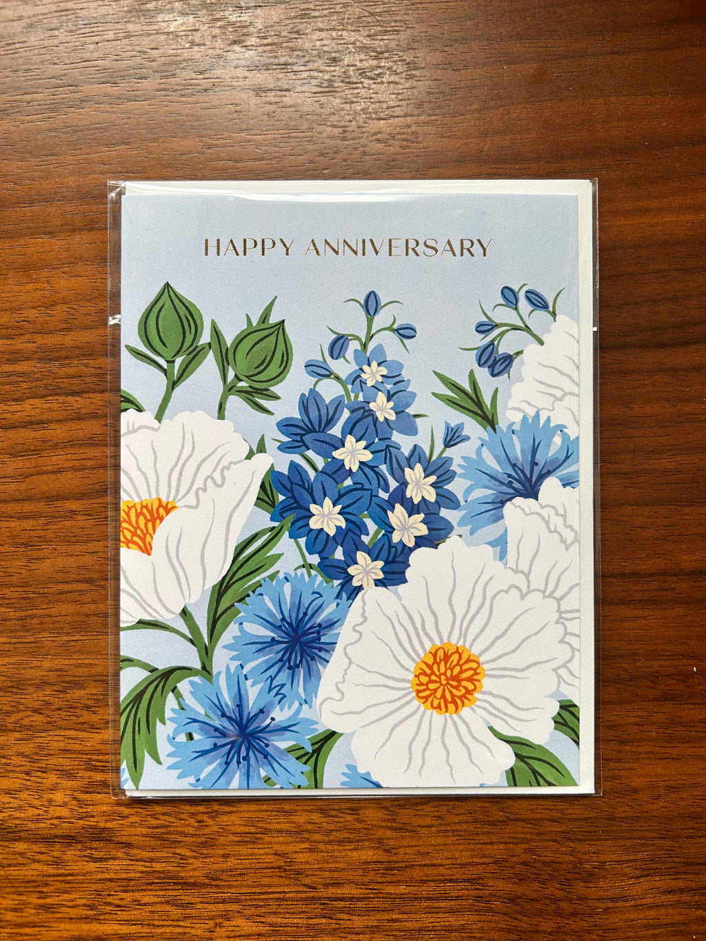 Floral anniversary greeting card featuring blue and white flowers on a soft blue background with the words "Happy Anniversary."