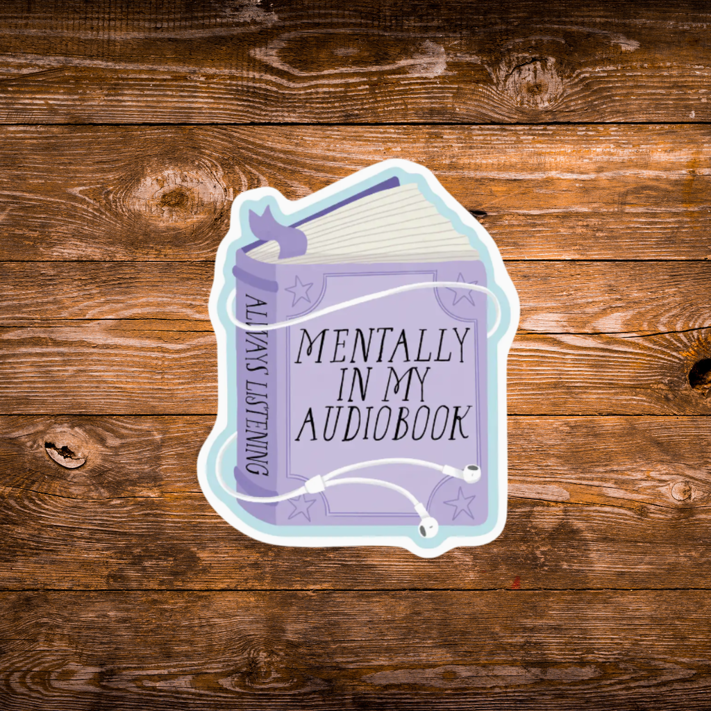 A die-cut sticker shaped like an audiobook book, featuring a lavender cover with the text 'MENTALLY IN MY AUDIOBOOK' and 'ALWAYS LISTENING' on the spine, shown on a rustic brown wooden background.