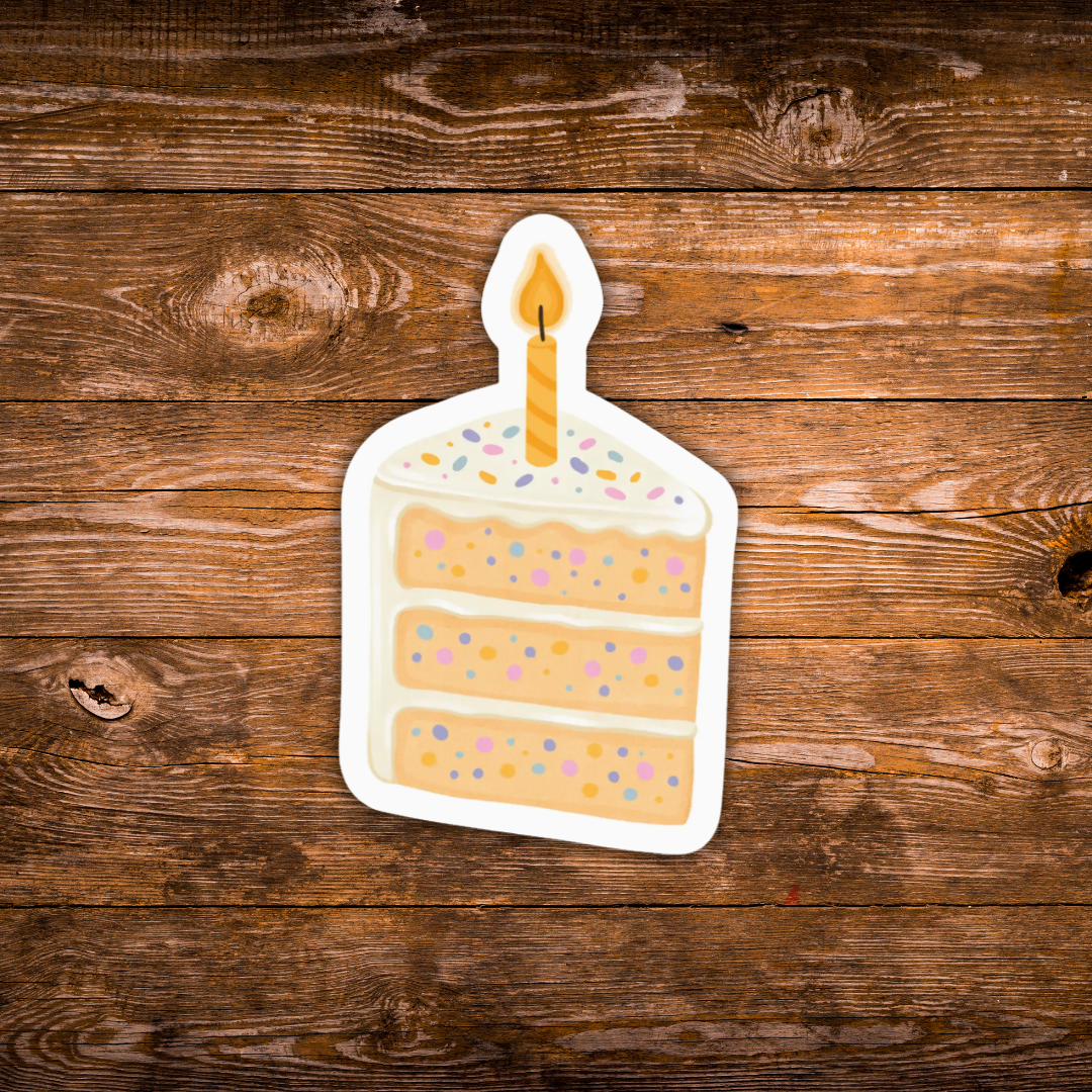 A die-cut sticker of a three-layer birthday cake slice with a single lit candle, shown on a rustic brown wooden background.