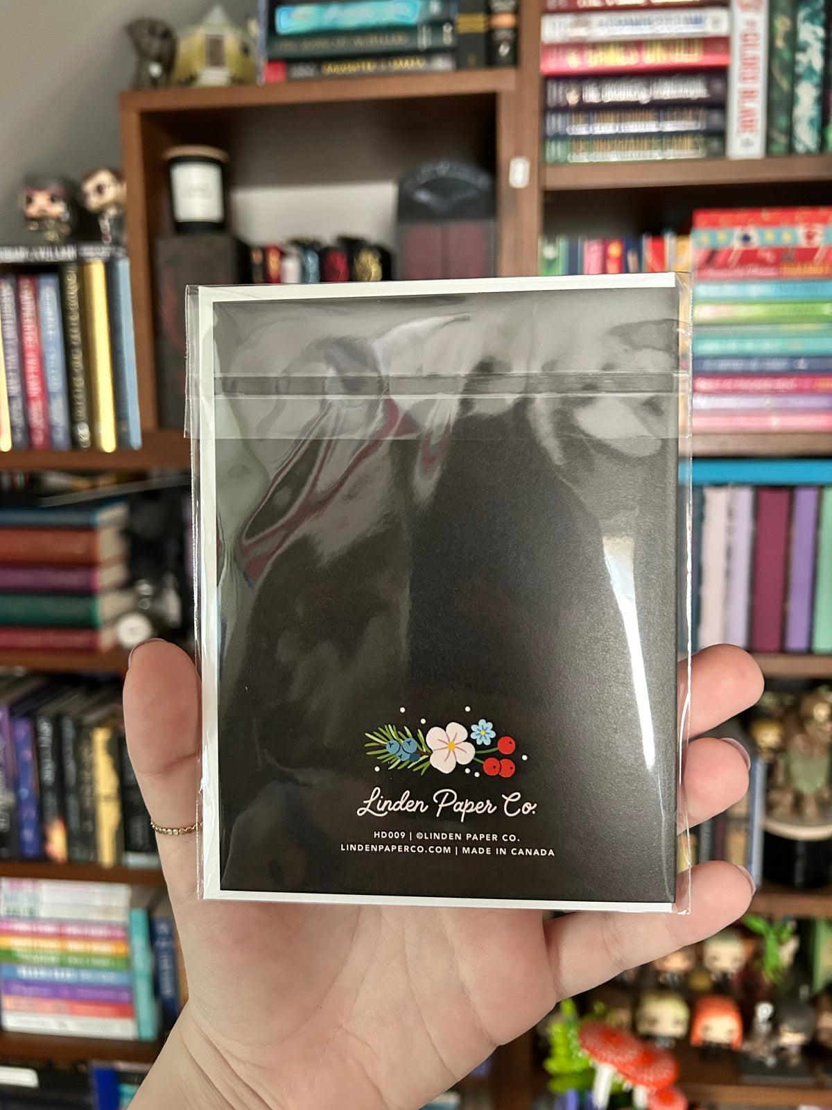 A hand holding a clear plastic-wrapped card by Linden Paper Co.