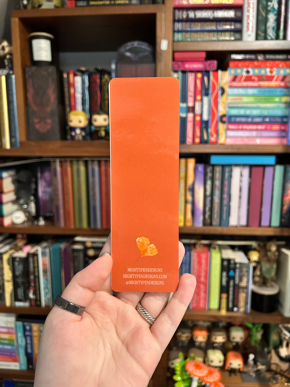 Back of autumn bookmark bright orange with a leaf illustration and Mighty Pen Designs information 