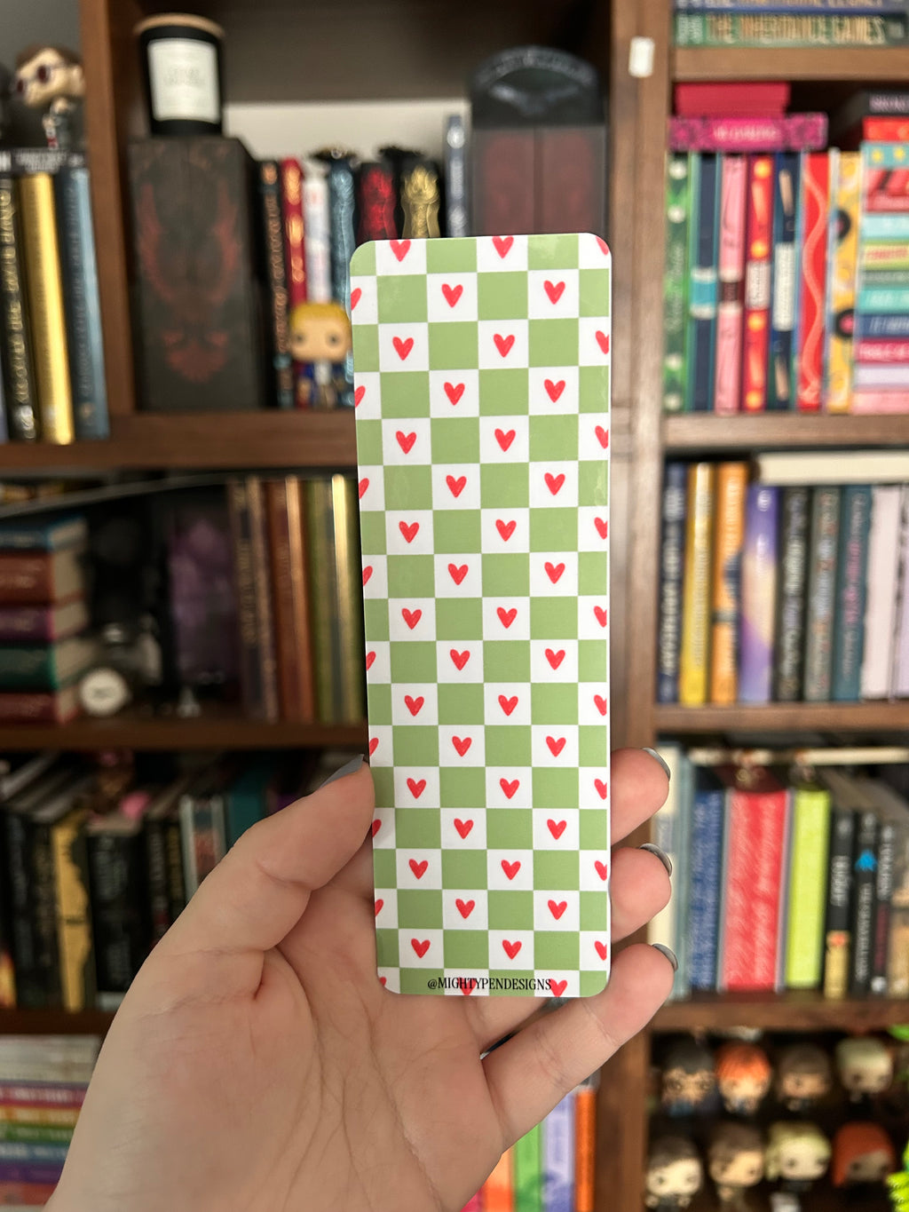 Double-sided frog bookmark featuring a cute green frog holding a cleaver in a mushroom-covered woodland scene with “Keep Reading” lettering, paired with a green checkerboard pattern and pink hearts.