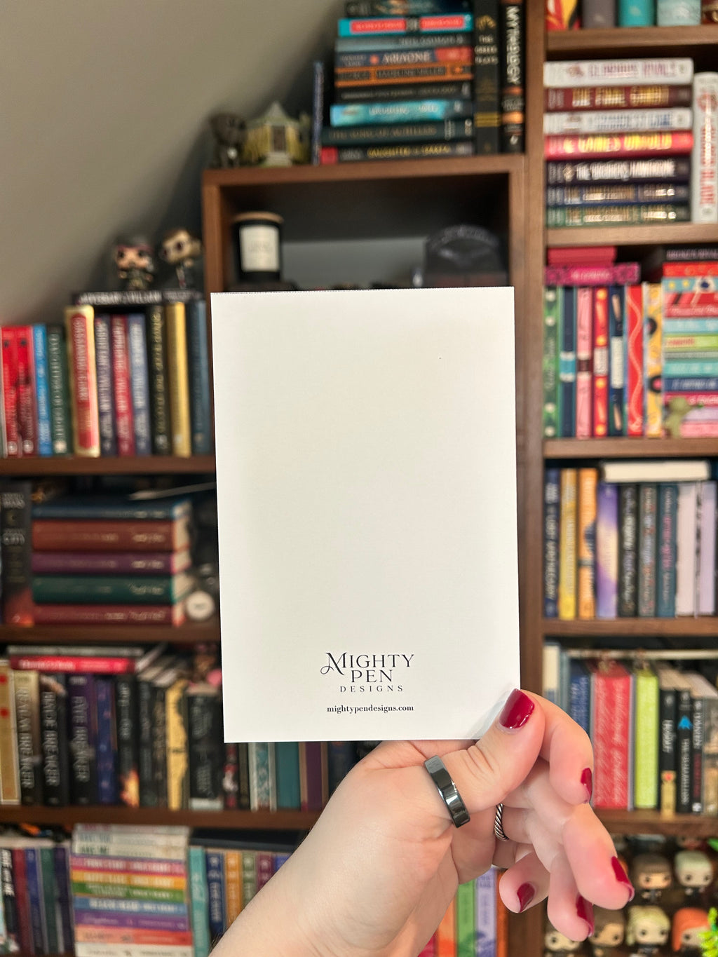 Back of white card with Mighty Pen Designs logo.