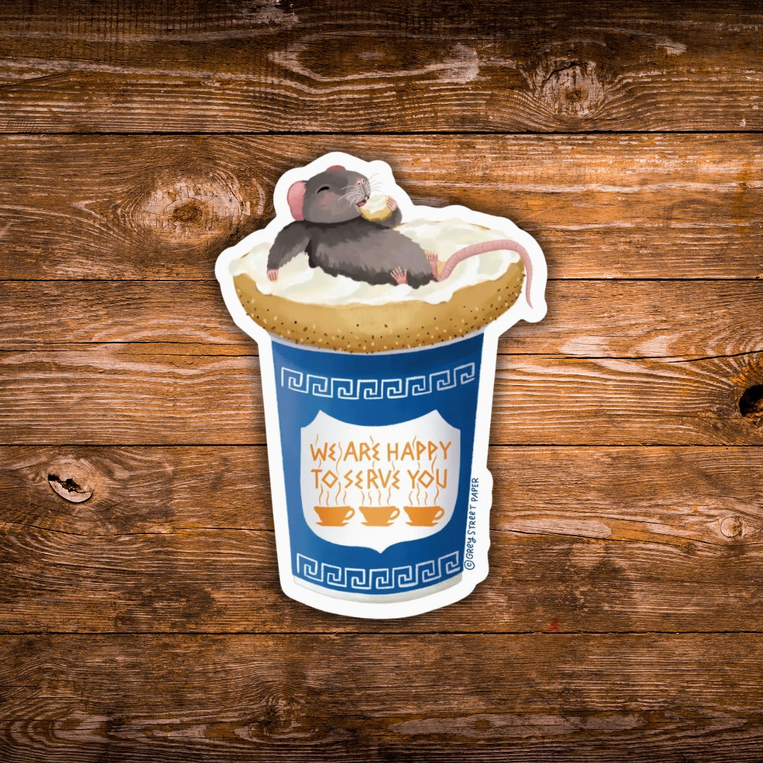 A die-cut sticker featuring a cartoon gray mouse lounging on a cup of coffee with an everything bagel on top, placed on a rustic brown wooden background. The sticker includes the text 'WE ARE HAPPY TO SERVE YOU'.