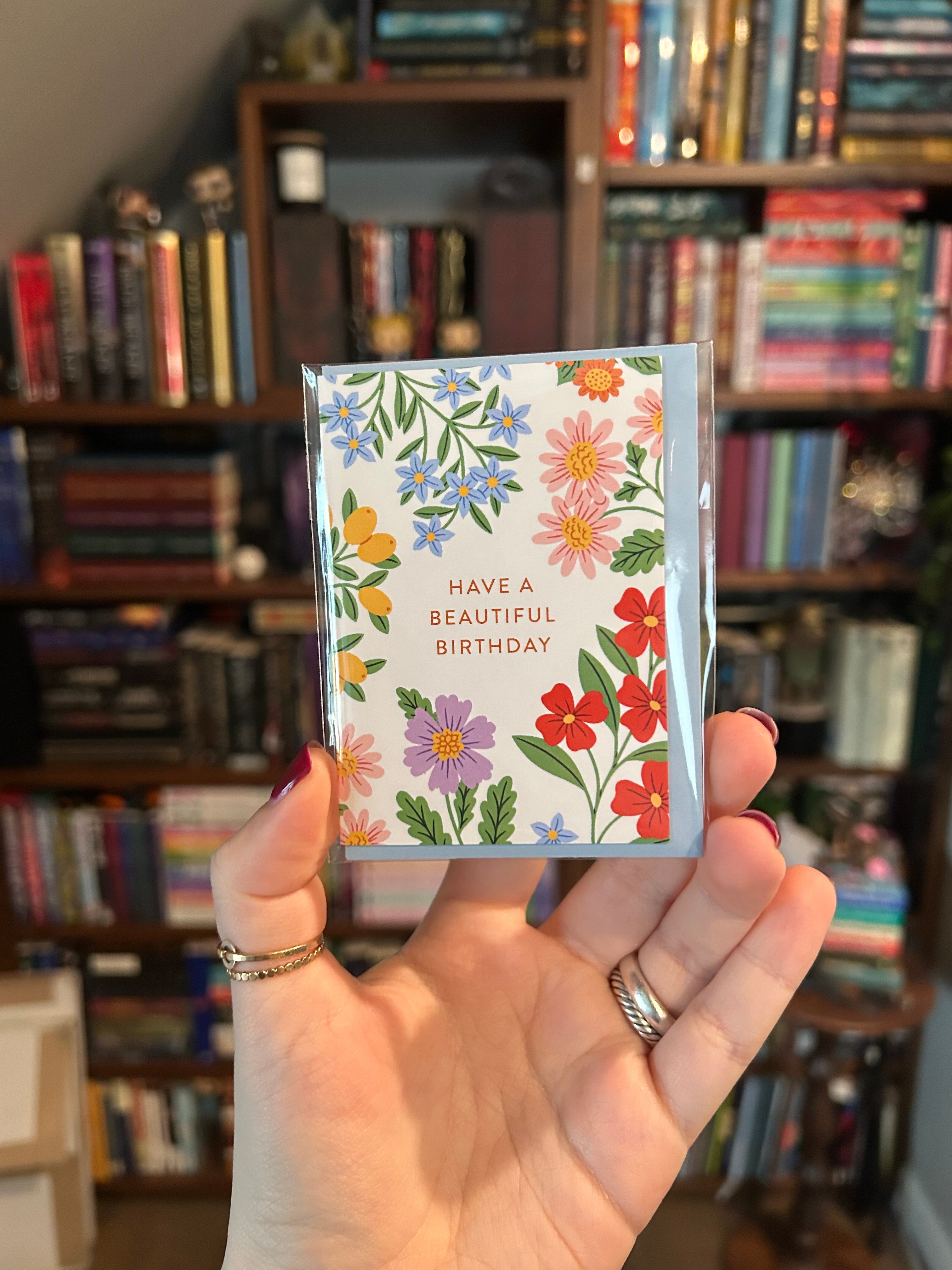 Mini birthday greeting card featuring colorful garden flowers surrounding the words "Have a Beautiful Birthday" on a white background.