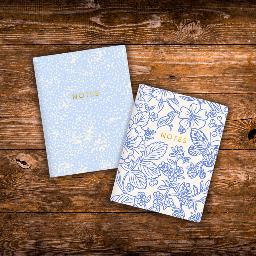 Set of two blue floral notebooks featuring coordinating floral cover designs with gold foil details, 44 blank pages each, and saddle stitched binding.