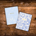 Set of two blue floral notebooks featuring coordinating floral cover designs with gold foil details, 44 blank pages each, and saddle stitched binding.