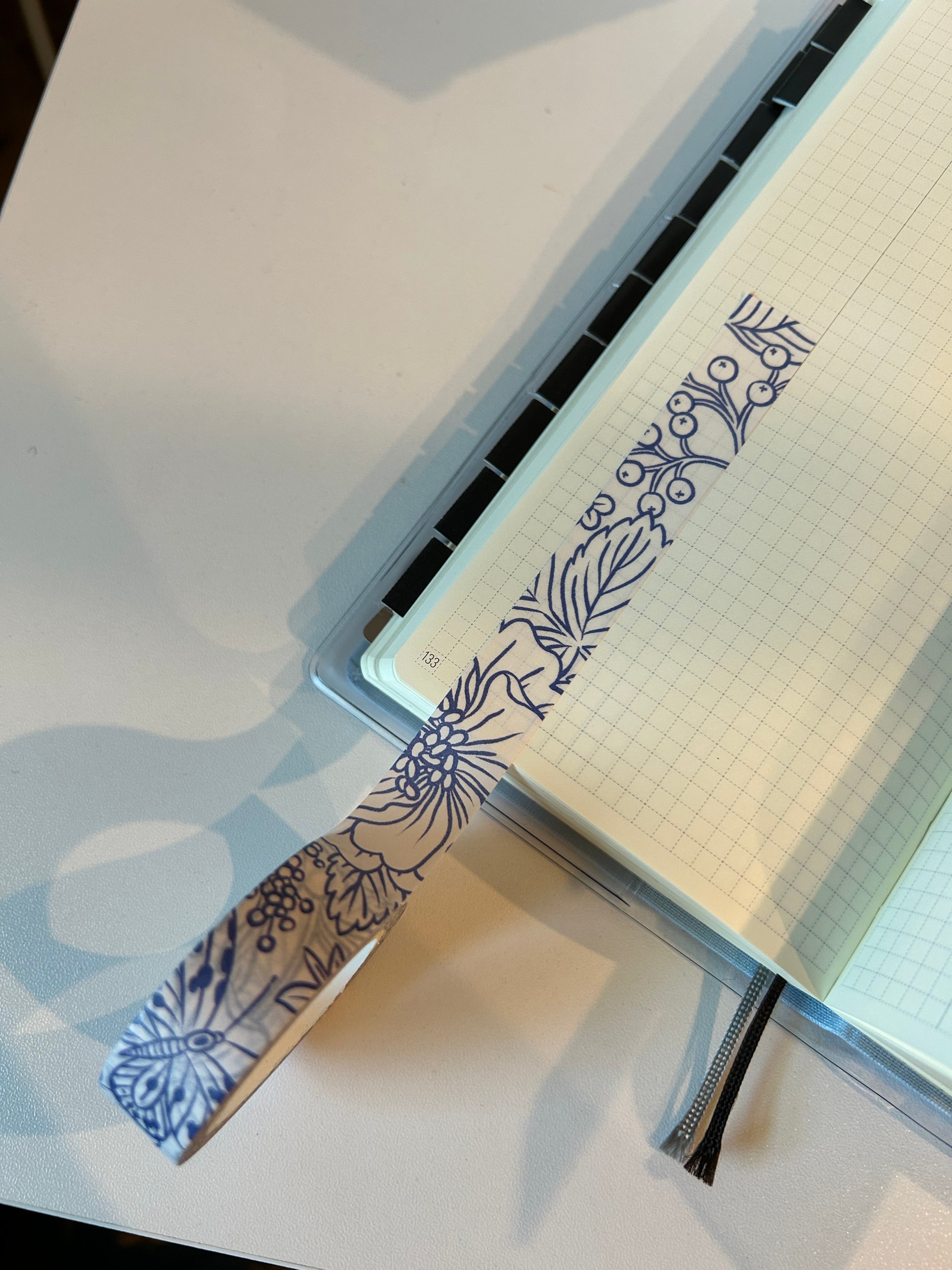 Decorative washi tape featuring blue botanical flowers, butterflies, berries, and leaves on a white background.