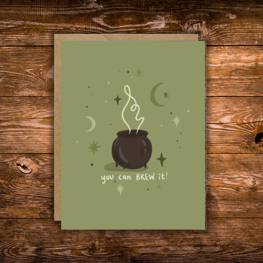 Encouragement greeting card featuring a bubbling cauldron surrounded by stars and crescent moons with the message "You Can Brew It!" on a sage green background.