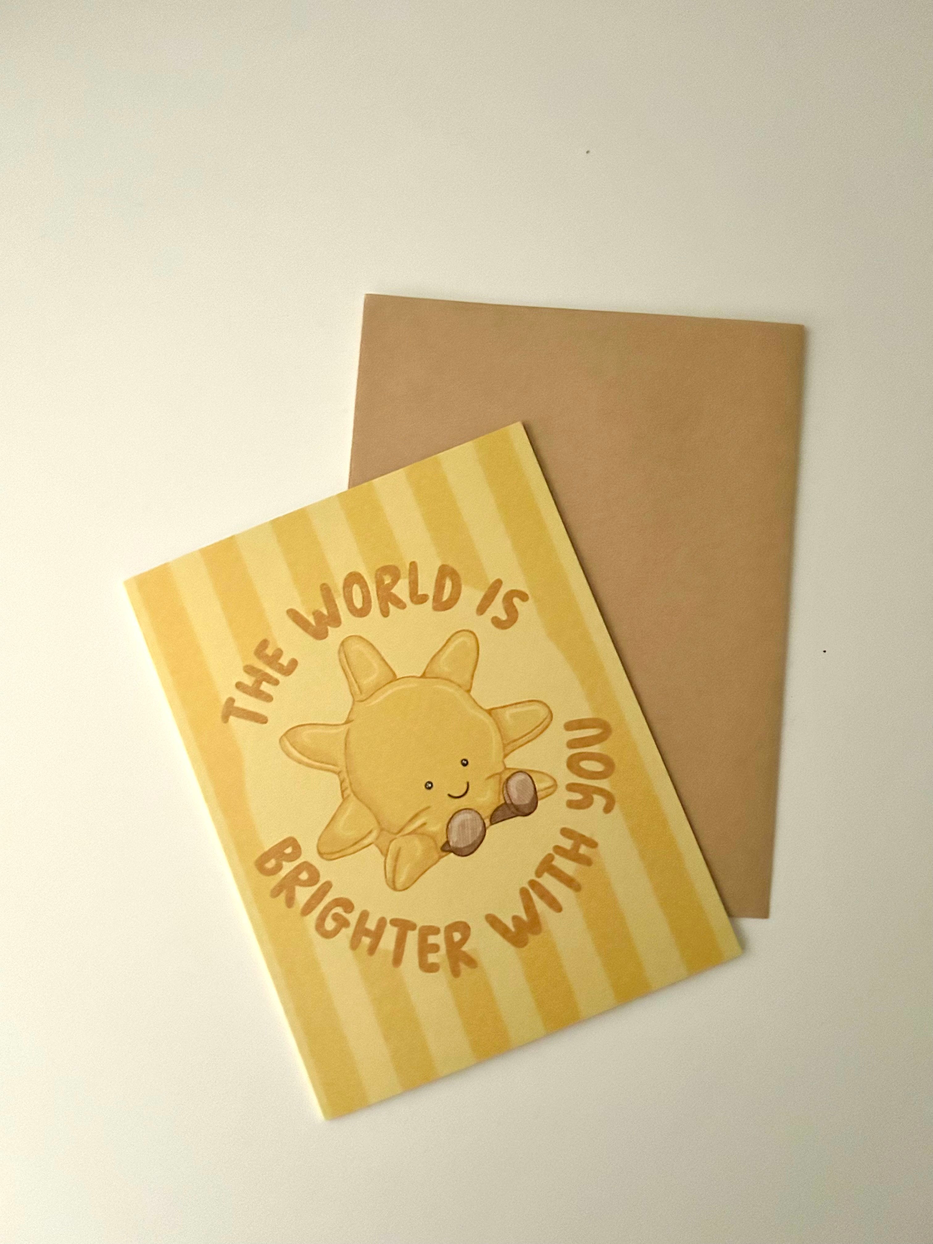 Cute encouragement greeting card featuring a smiling sunshine with the message "The World Is Brighter With You" on a soft yellow striped background.