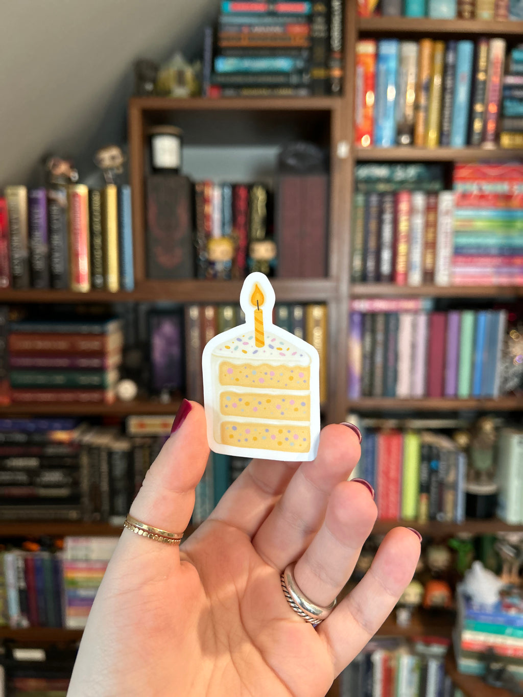 Waterproof vinyl sticker featuring a pastel slice of birthday cake with sprinkles and a lit candle. 