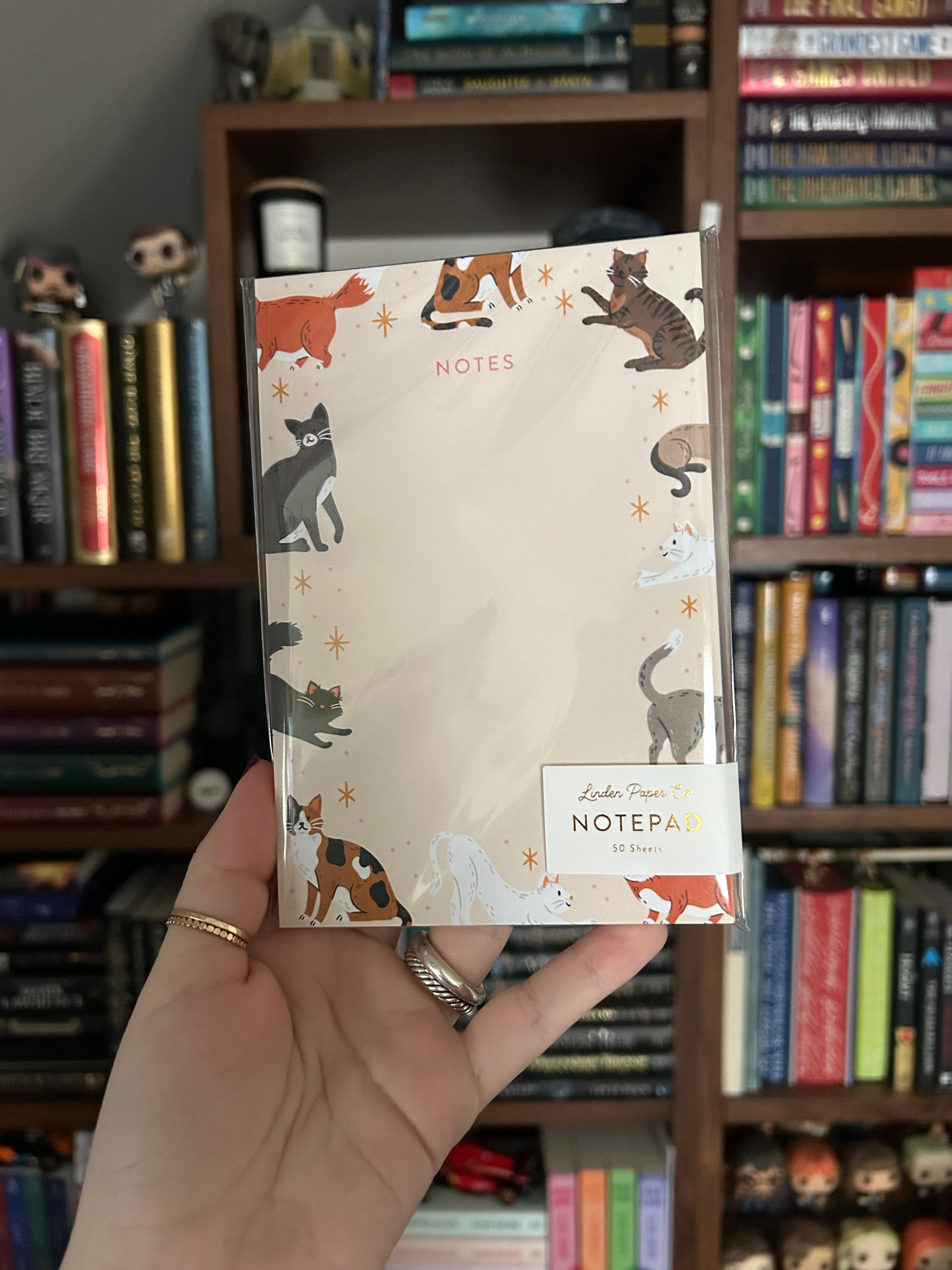 Tear-away notepad featuring playful illustrated cats around the border with an open center for writing notes.