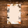 Tear-away notepad featuring playful illustrated cats around the border with an open center for writing notes.
