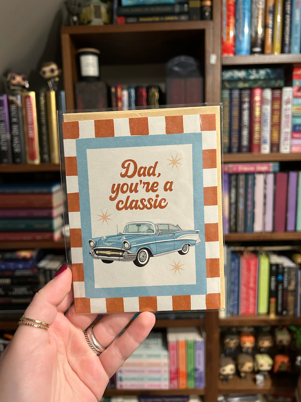 Father's Day greeting card featuring a vintage blue classic car with the message "Dad, You're a Classic" on a retro striped background.