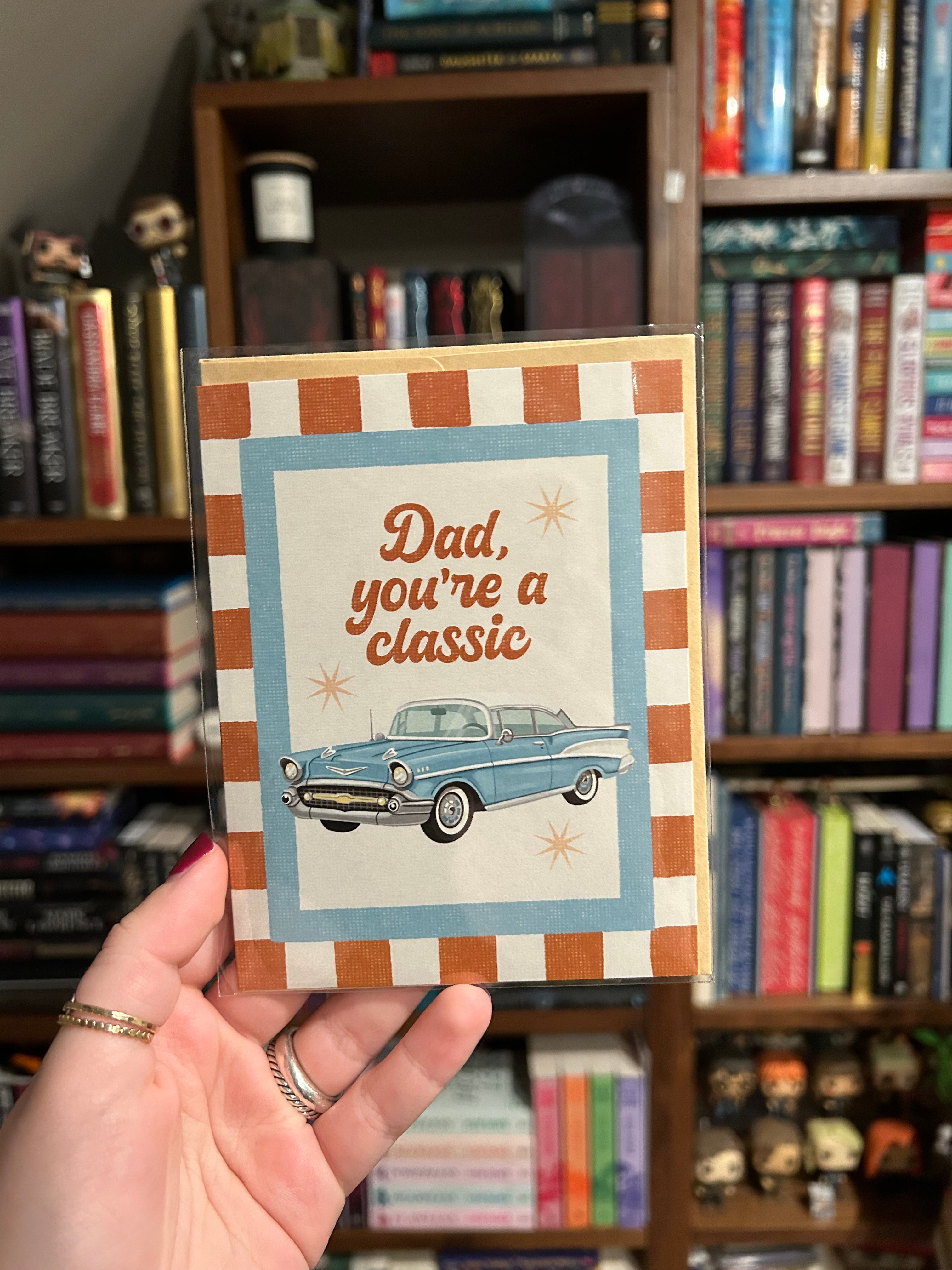 Father's Day greeting card featuring a vintage blue classic car with the message "Dad, You're a Classic" on a retro striped background.