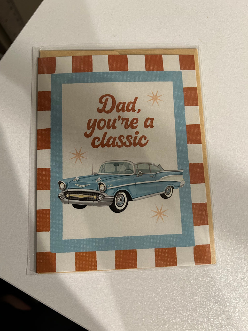 Father's Day greeting card featuring a vintage blue classic car with the message "Dad, You're a Classic" on a retro striped background.