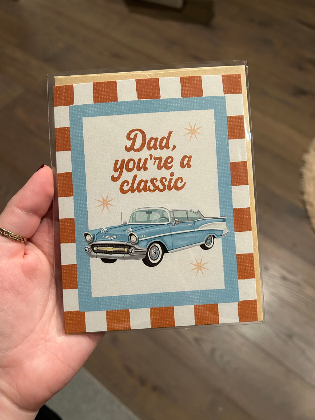 Father's Day greeting card featuring a vintage blue classic car with the message "Dad, You're a Classic" on a retro striped background.
