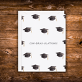 Graduation greeting card featuring a repeating pattern of graduation caps with the pun "Con-Grad-Ulations!" centered on a white background.
