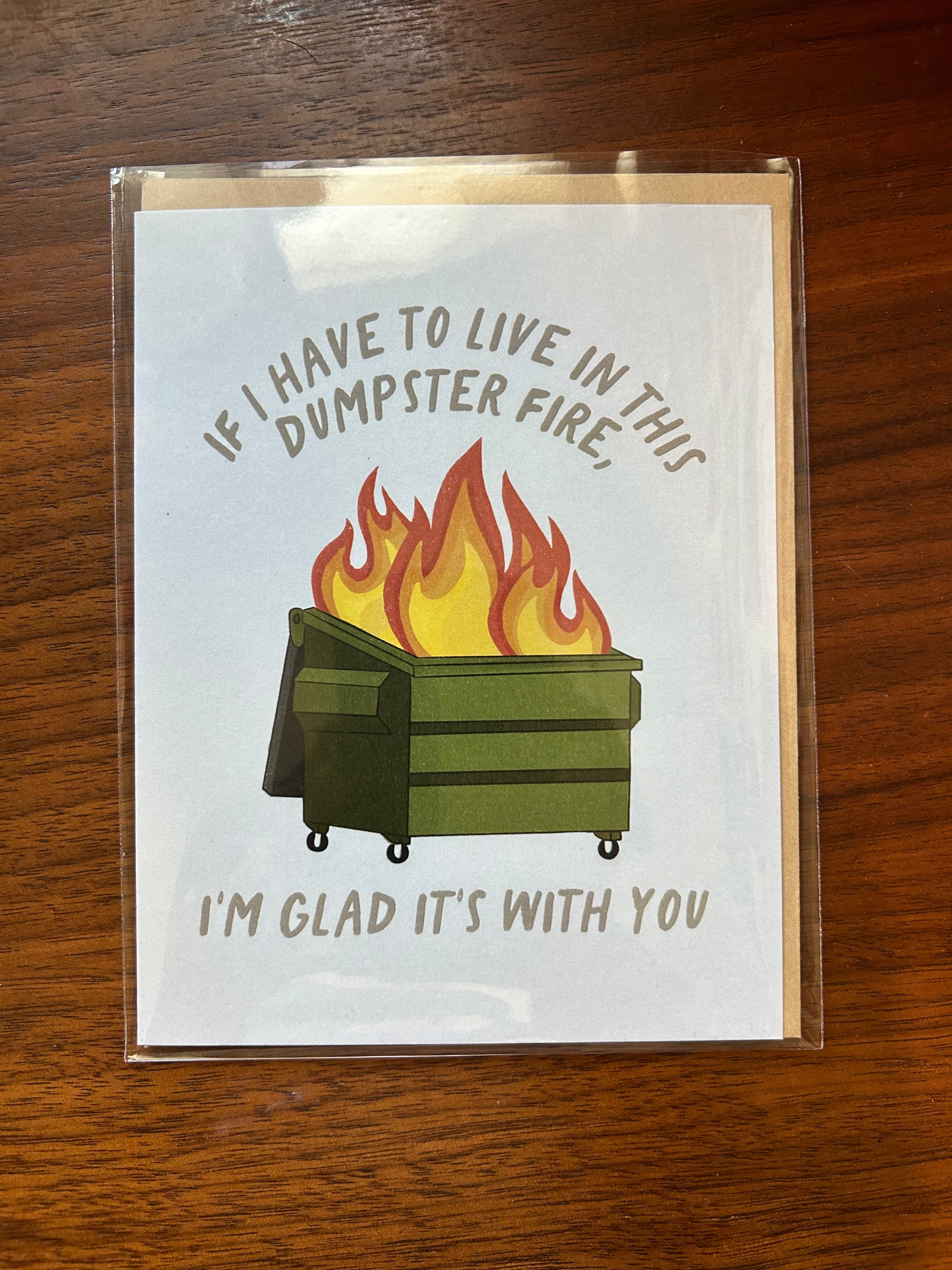 Funny greeting card featuring a flaming green dumpster with the message, "If I Have to Live in This Dumpster Fire, I'm Glad It's With You."