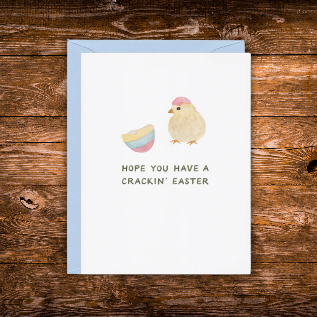 Cute Easter greeting card featuring a fluffy baby chick wearing an eggshell hat beside a cracked pastel Easter egg with the message "Hope You Have a Crackin' Easter."