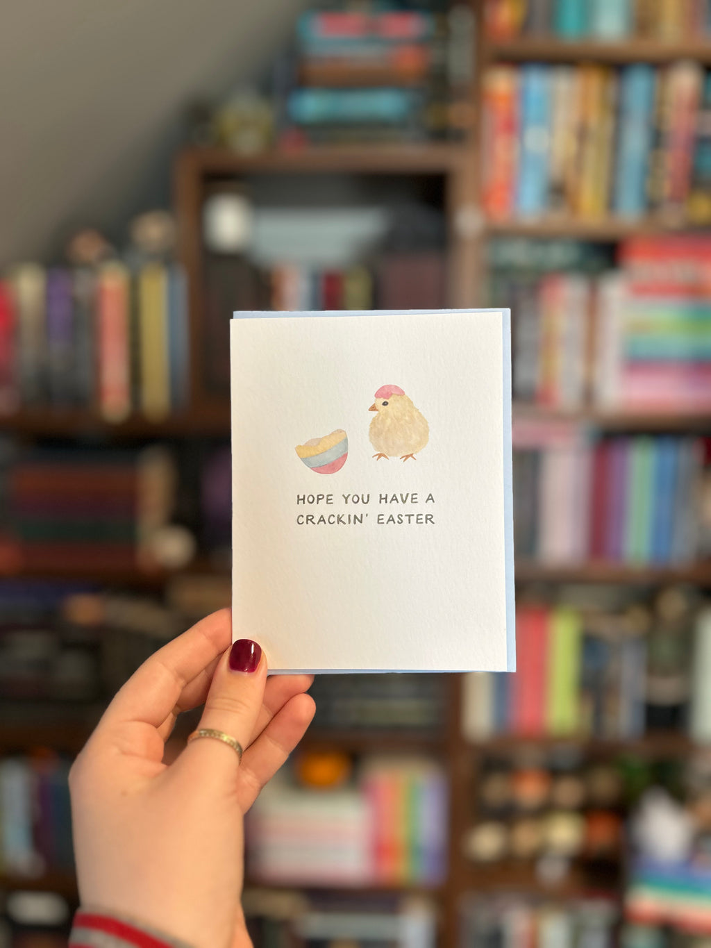 Cute Easter greeting card featuring a fluffy baby chick wearing an eggshell hat beside a cracked pastel Easter egg with the message "Hope You Have a Crackin' Easter."
