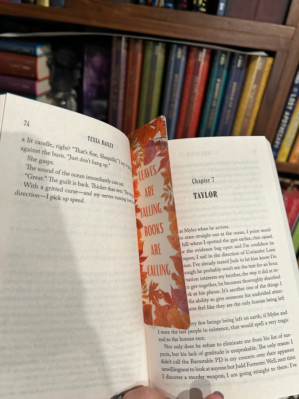 Autumn bookmark with colorful fall leaves and the phrase “Leaves Are Falling, Books Are Calling” laying in between the pages of a book