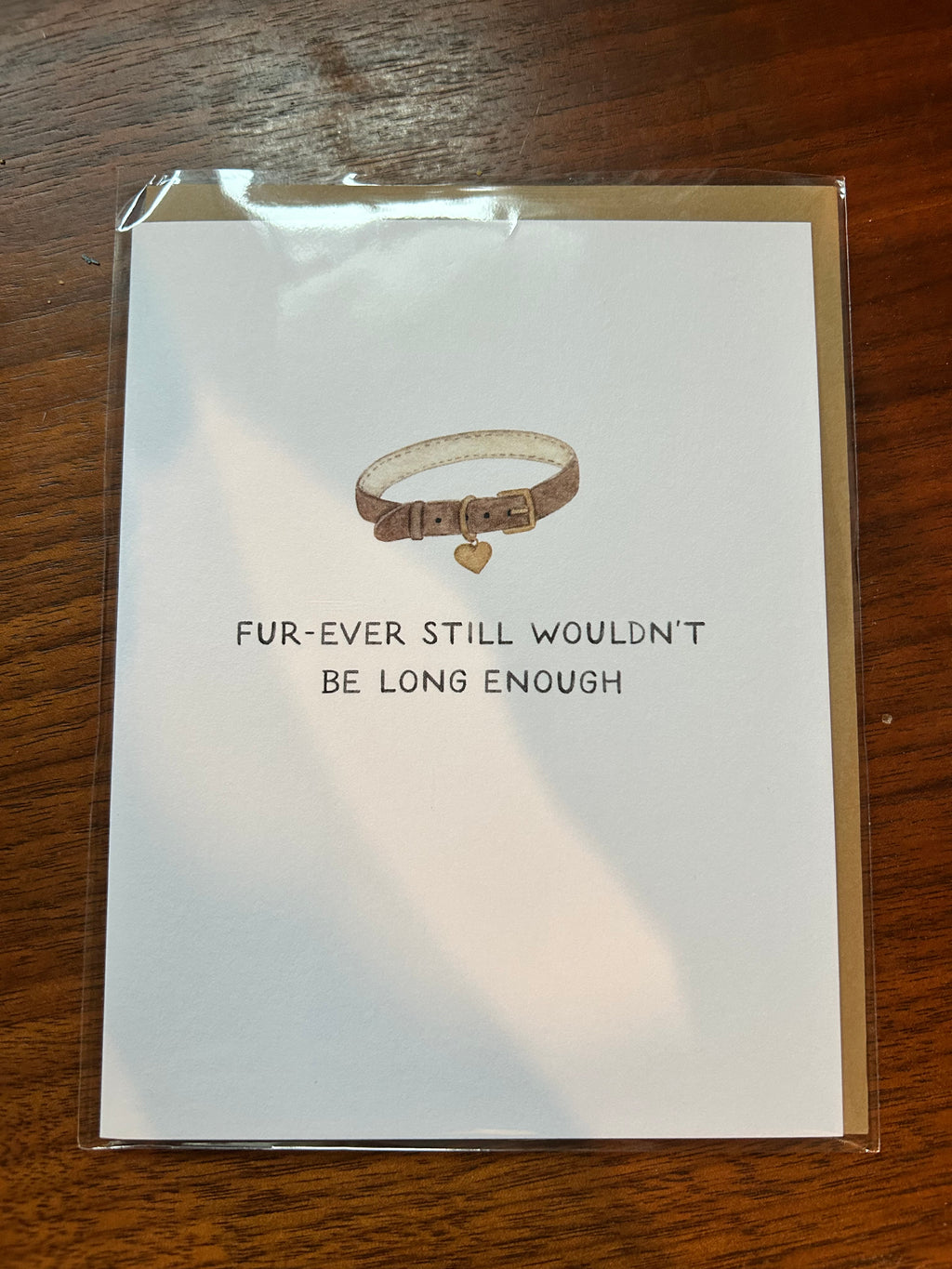 Minimalist pet sympathy greeting card featuring a brown pet collar with a heart-shaped tag and the message "Fur-Ever Still Wouldn't Be Long Enough" on a white background.