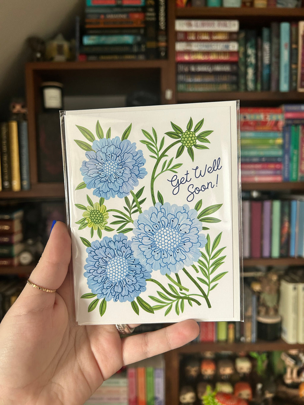 Blue floral Get Well Soon greeting card featuring illustrated flowers and greenery.