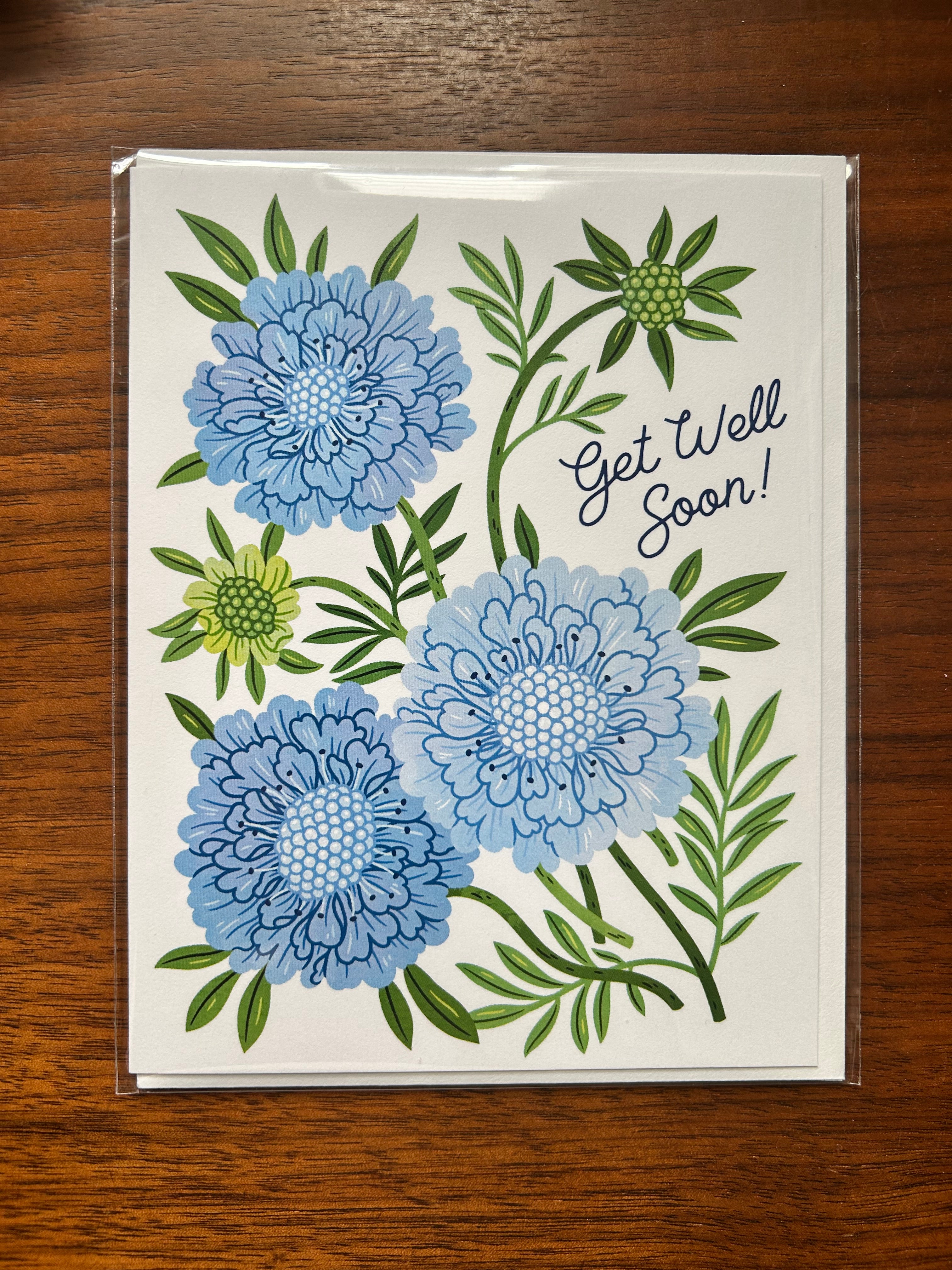 Blue floral Get Well Soon greeting card featuring illustrated flowers and greenery.
