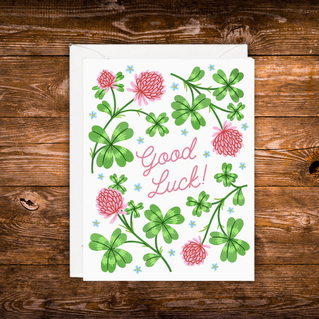 Good luck greeting card featuring green clovers, pink flowers, and the words "Good Luck!"