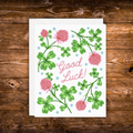 Good luck greeting card featuring green clovers, pink flowers, and the words "Good Luck!"