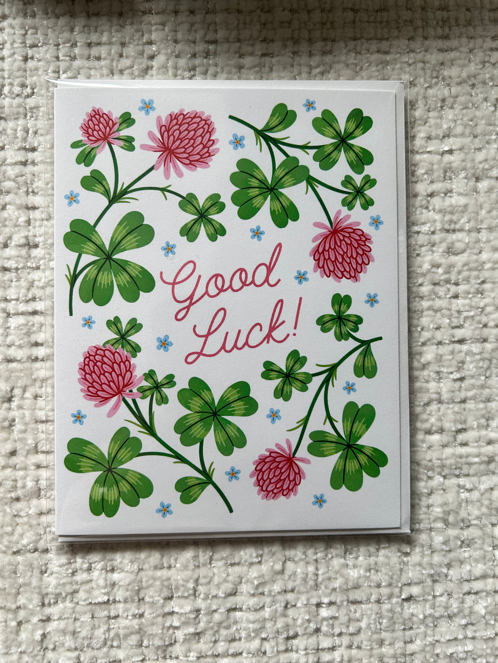 Good luck greeting card featuring green clovers, pink flowers, and the words "Good Luck!"