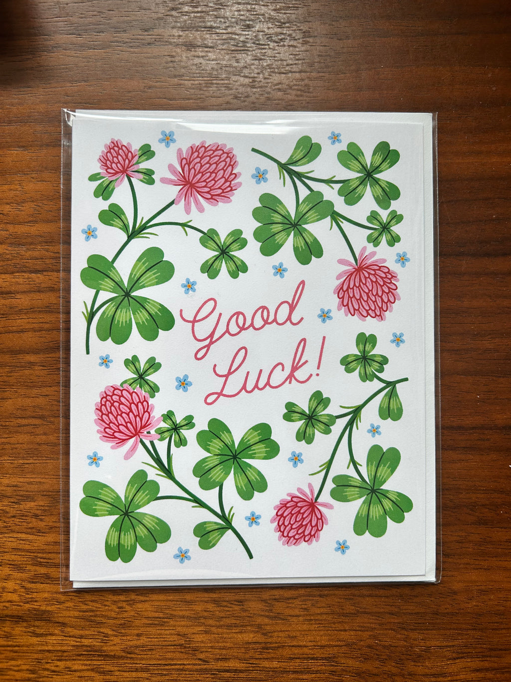 Good luck greeting card featuring green clovers, pink flowers, and the words "Good Luck!"