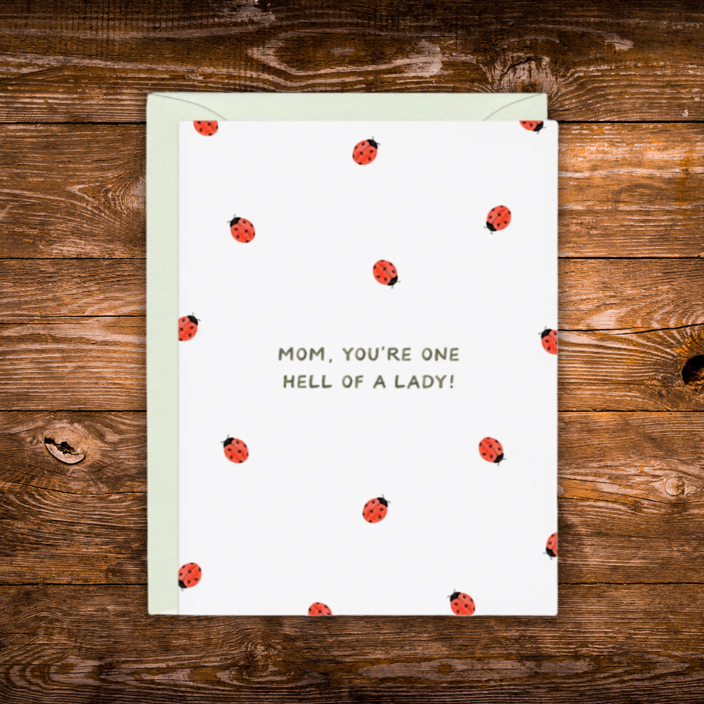 Funny Mother's Day greeting card featuring scattered ladybugs and the message "Mom, You're One Hell of a Lady!" on a white background.