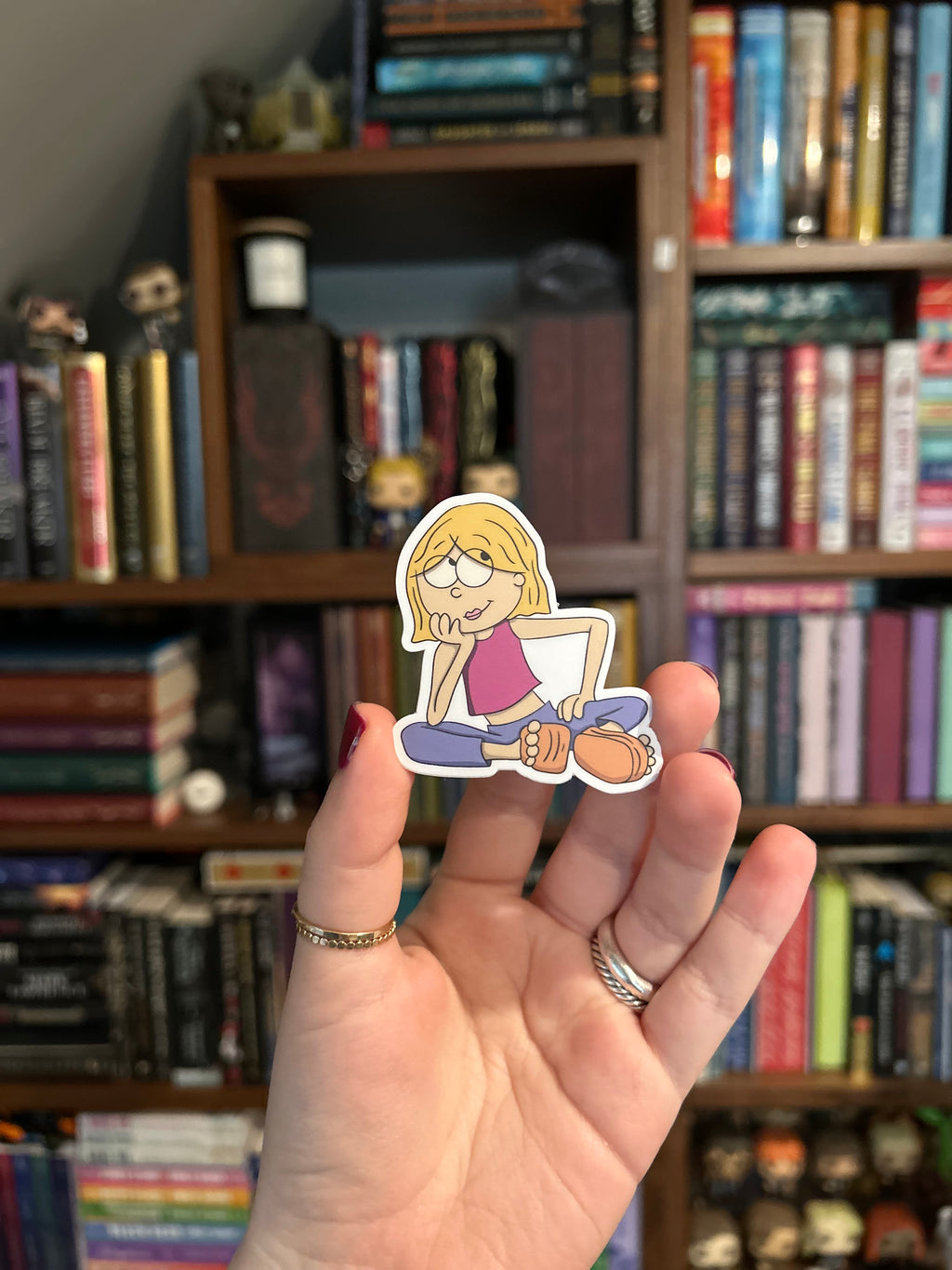 Waterproof vinyl sticker featuring a retro-inspired cartoon girl sitting cross-legged with blonde hair, purple top, and blue pants.