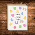 Cute romantic greeting card featuring colorful lucky charms including four-leaf clovers, horseshoes, rainbows, stars, hearts, and moons surrounding the message "I'm So Lucky You're Mine."