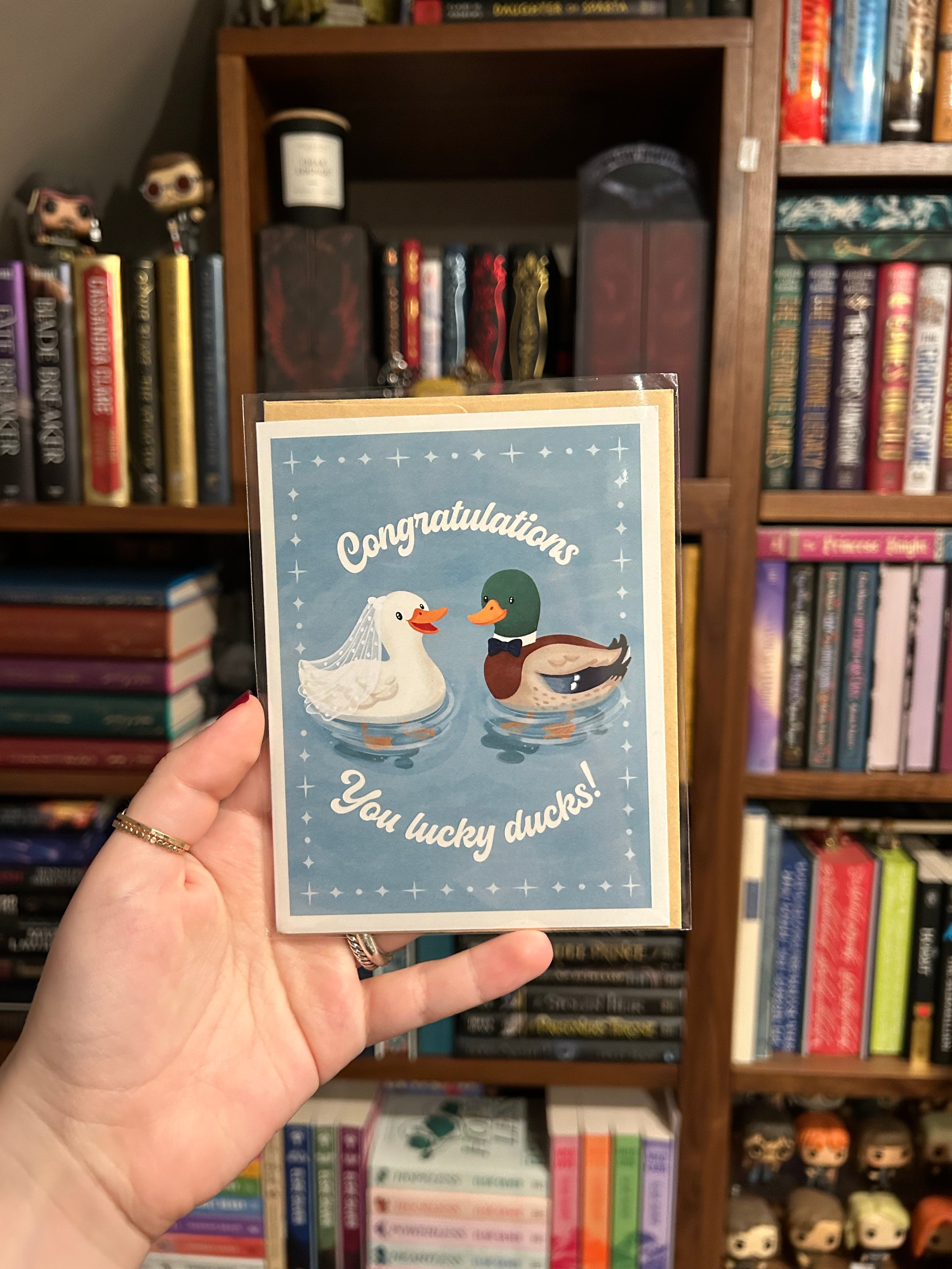 Wedding congratulations greeting card featuring a bride duck wearing a veil and a groom duck wearing a bow tie with the phrase "Congratulations You Lucky Ducks!"