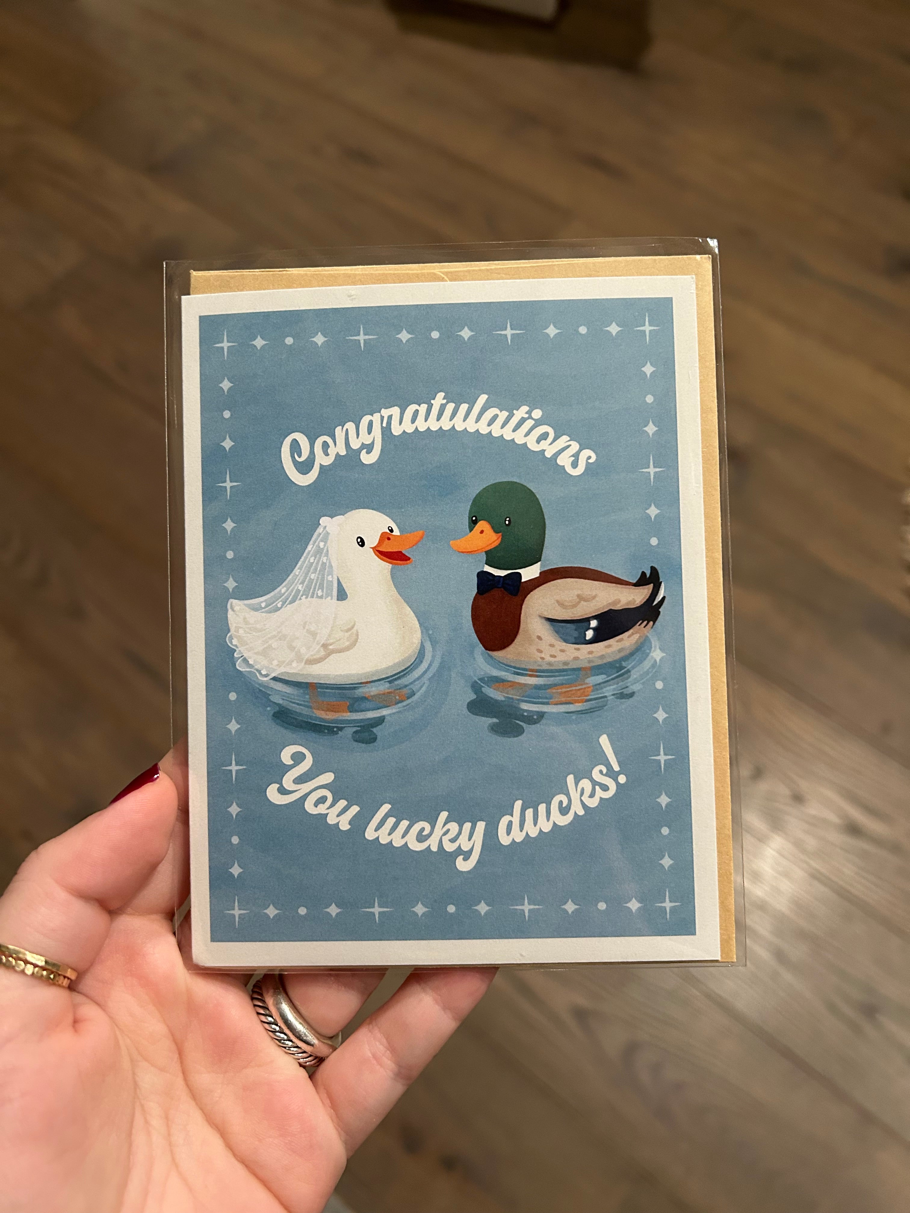 Wedding congratulations greeting card featuring a bride duck wearing a veil and a groom duck wearing a bow tie with the phrase "Congratulations You Lucky Ducks!"