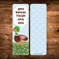 Double-sided mallard duck bookmark featuring a green-headed duck holding a tiny knife beneath the words “You better finish this one,” standing in a daisy meadow, with a white heart pattern on a light blue reverse.