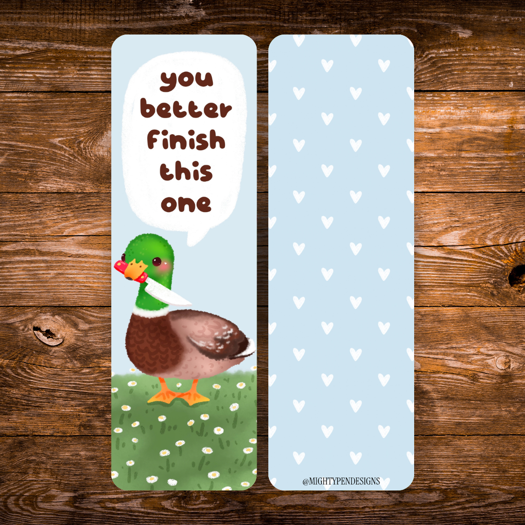 Double-sided mallard duck bookmark featuring a green-headed duck holding a tiny knife beneath the words “You better finish this one,” standing in a daisy meadow, with a white heart pattern on a light blue reverse.