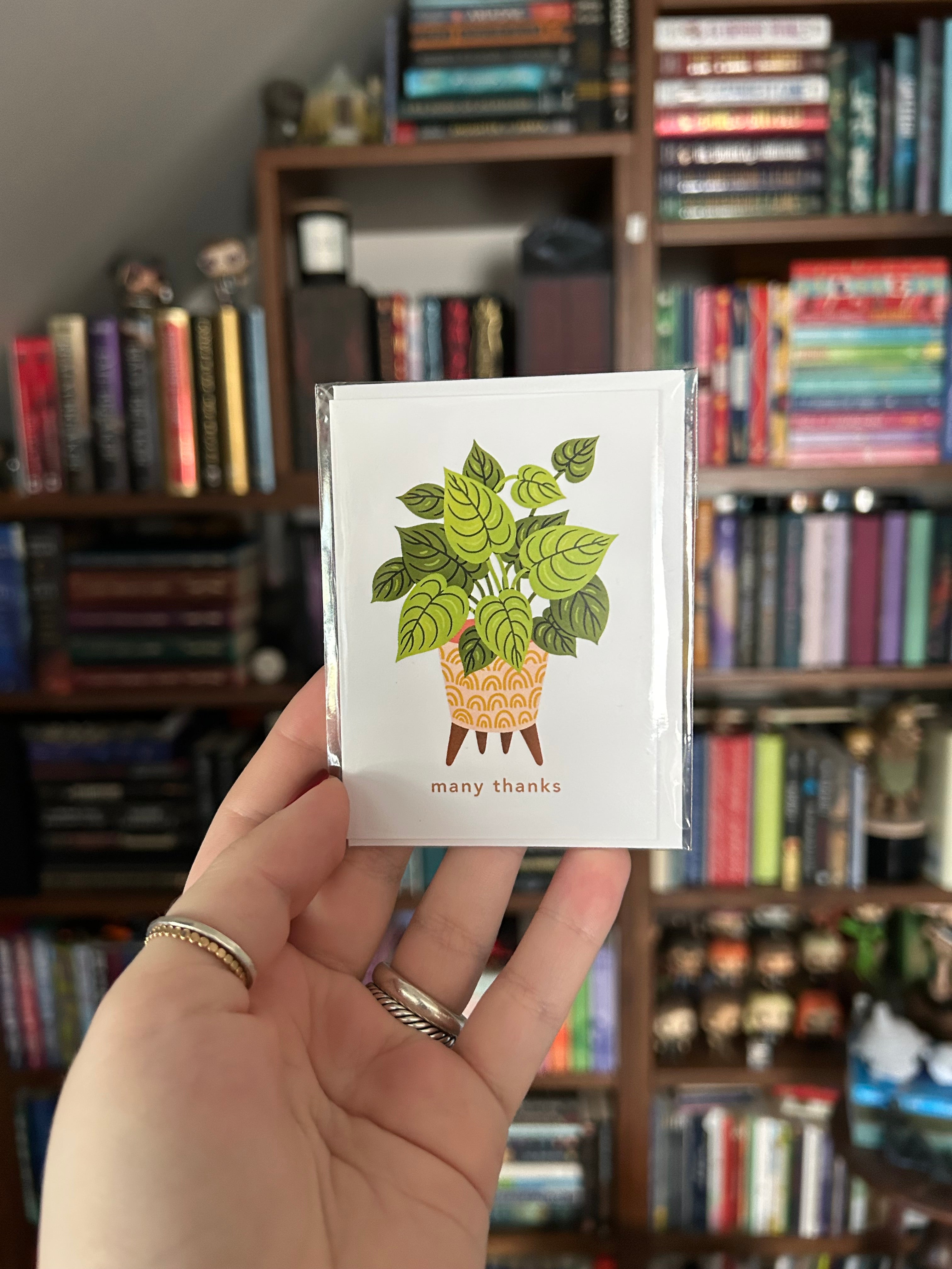 Mini greeting card featuring a green houseplant in a decorative yellow planter with the words "many thanks" beneath it on a white background.