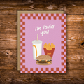 Cute romantic greeting card featuring an illustrated burger, fries, and soda with the message "I'm Lovin' You" on a retro pink background with a checkerboard border.