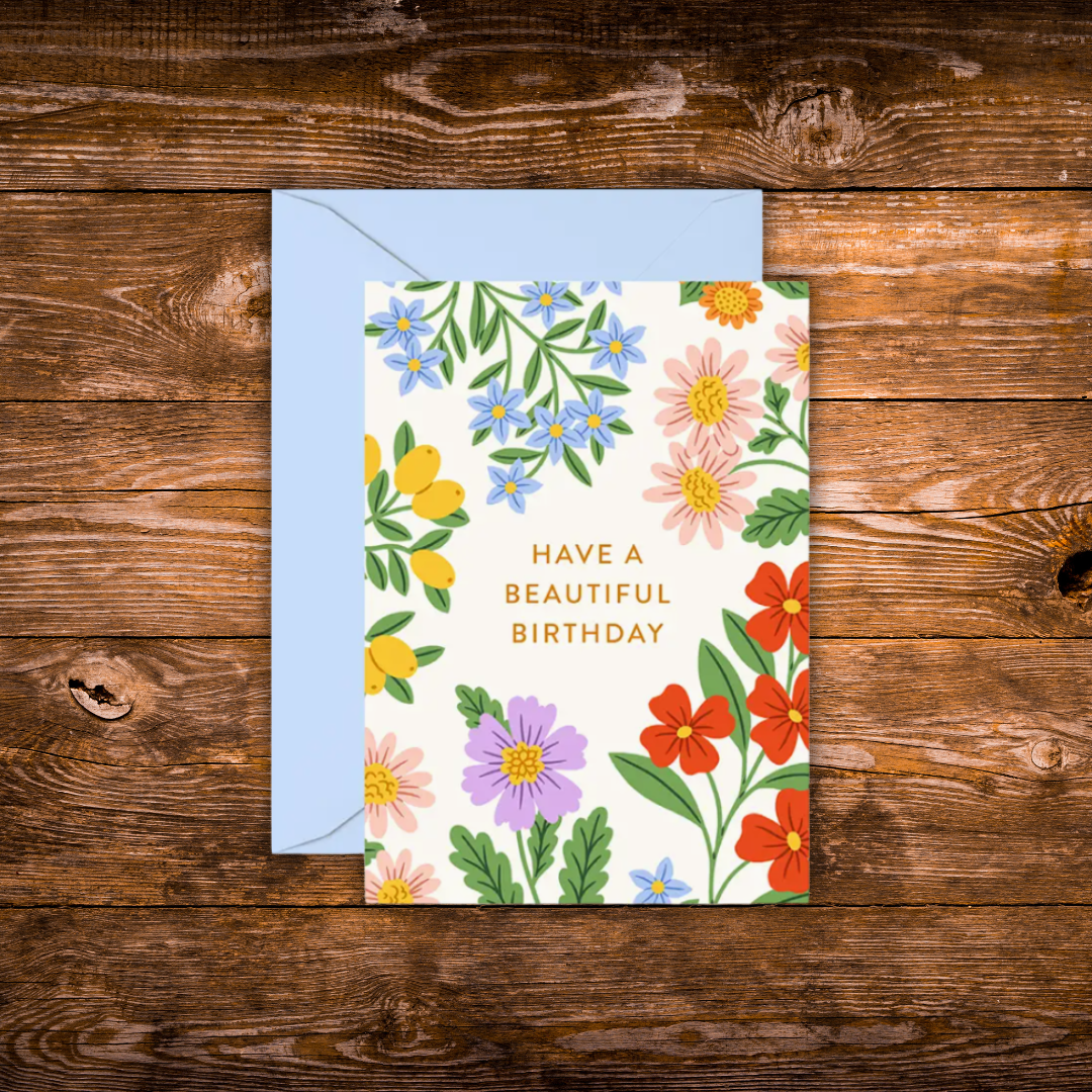 Mini birthday greeting card featuring colorful garden flowers surrounding the words "Have a Beautiful Birthday" on a white background.