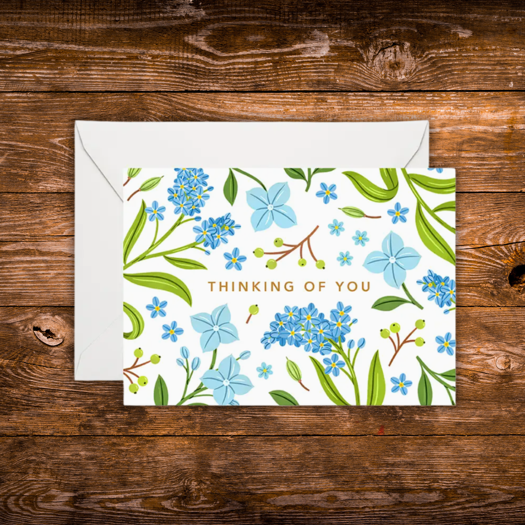 Mini landscape greeting card featuring blue floral illustrations surrounding the words "Thinking of You" on a white background.