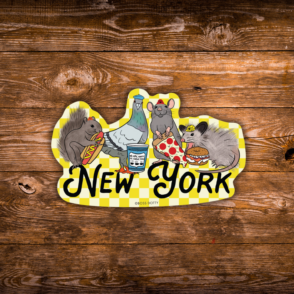 A die-cut sticker featuring cartoon animals and the words 'New York' on a yellow-and-white checkered background, placed on a rustic brown wood surface.