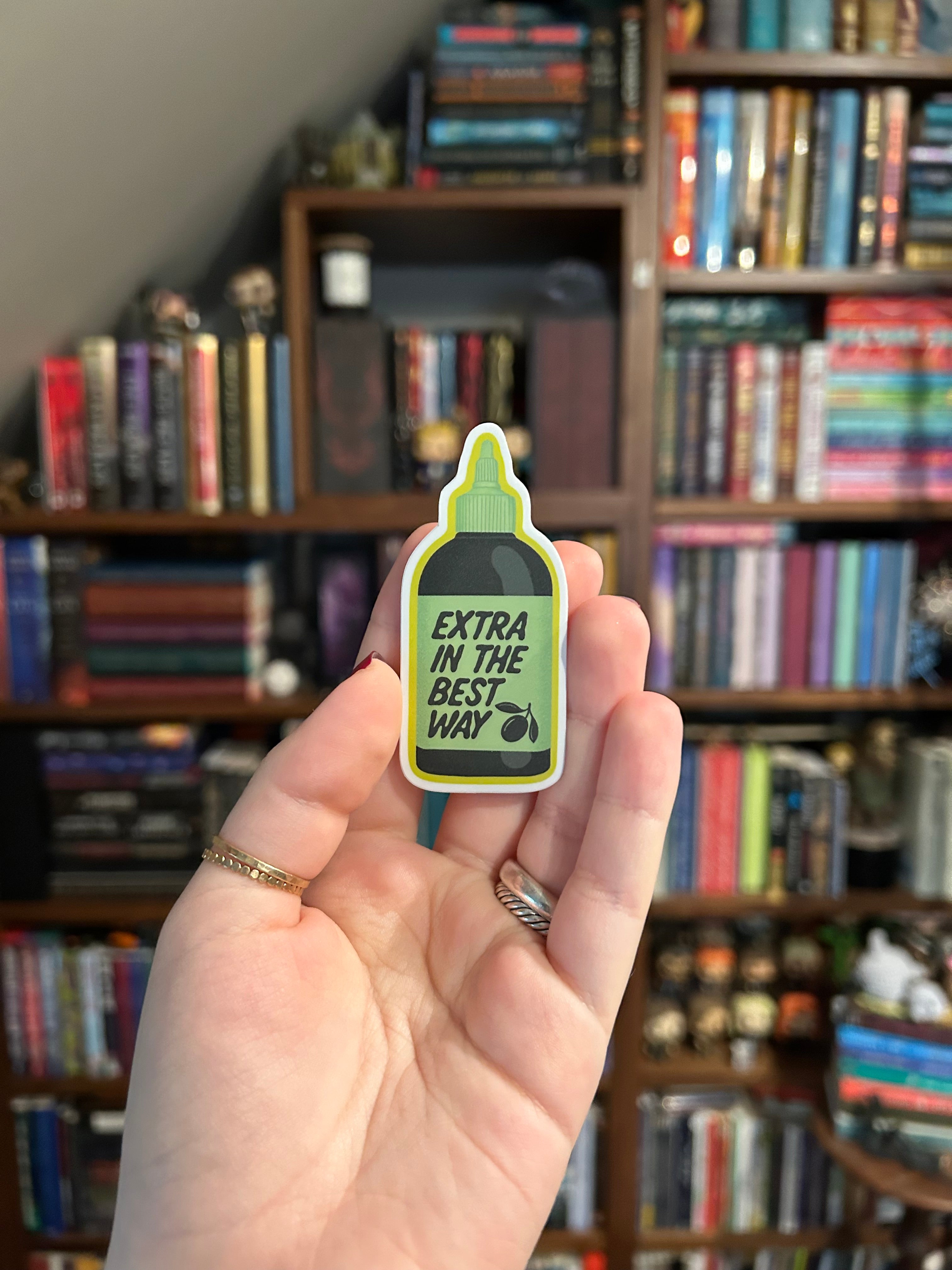 Waterproof vinyl sticker shaped like an olive oil bottle with the phrase "Extra In The Best Way" in green lettering on a light green label.