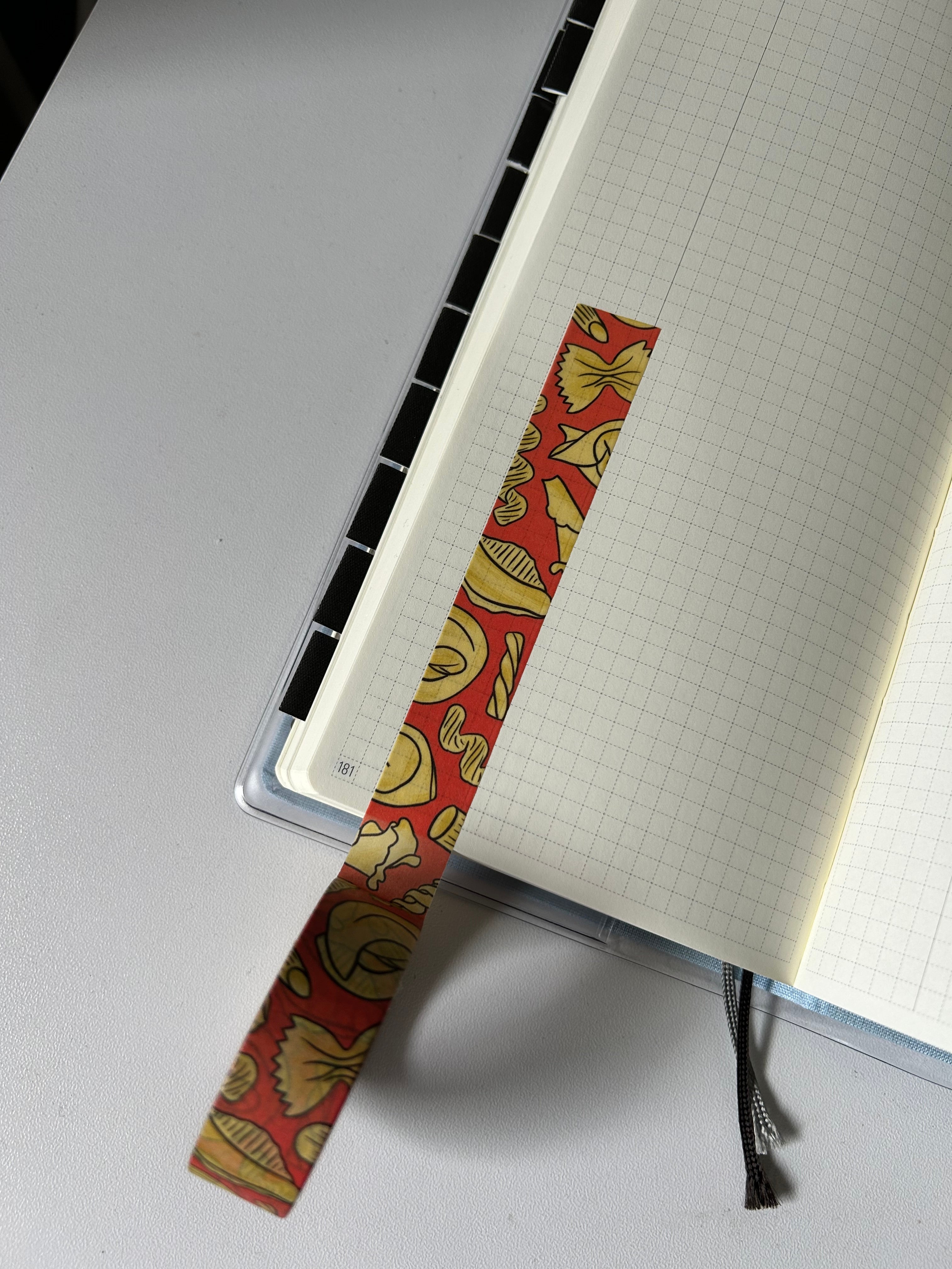 Decorative washi tape featuring illustrated pasta shapes including ravioli, rigatoni, fusilli, shells, and farfalle on a red background.
