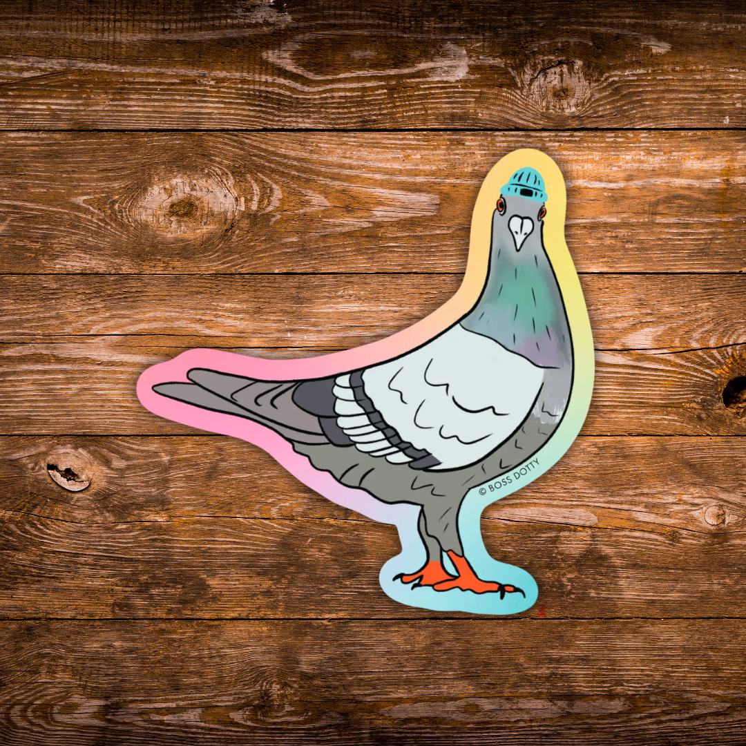 A die-cut sticker of a stylized pigeon with a rainbow gradient outline, placed on a rustic brown wooden plank background.