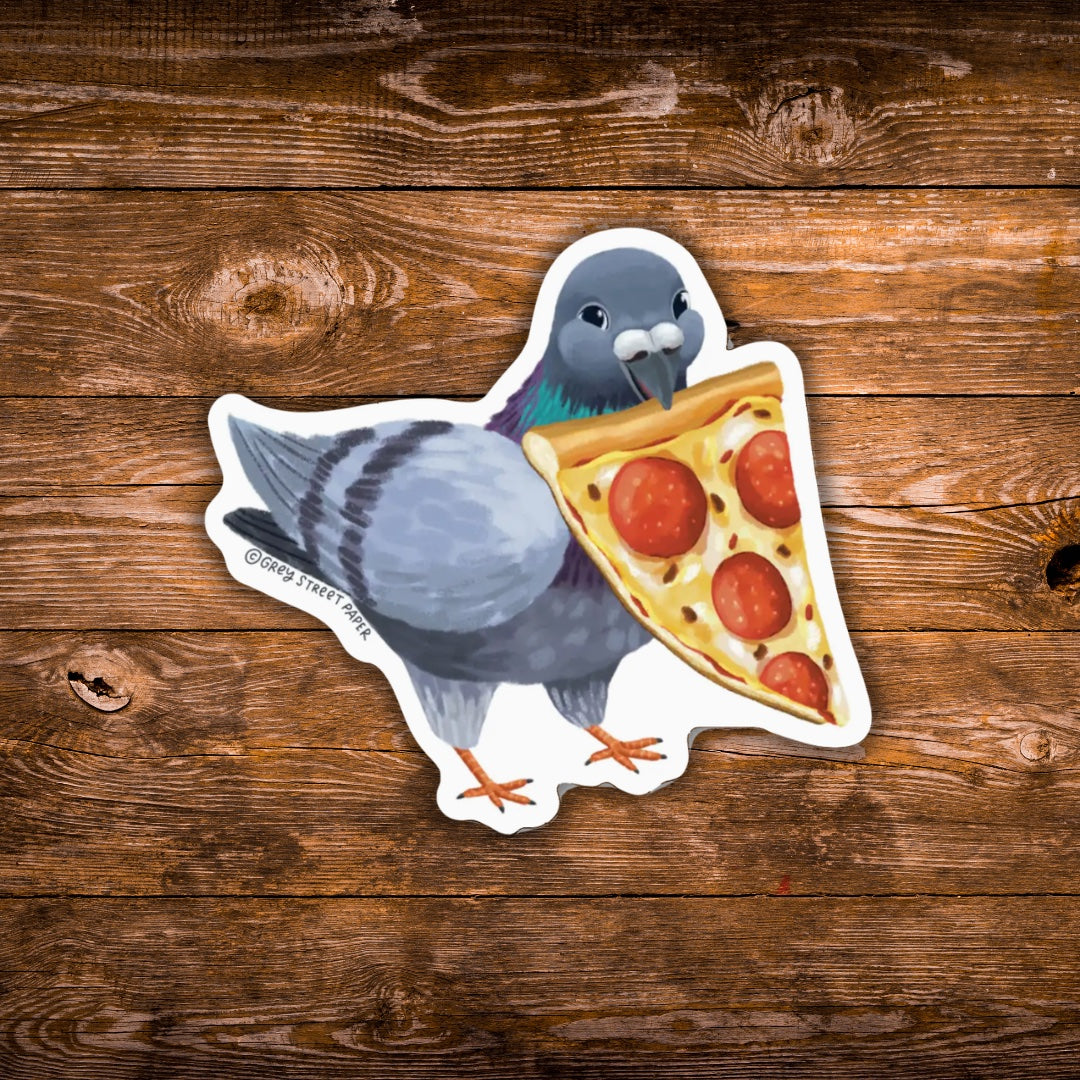 A die-cut sticker featuring an illustration of a gray pigeon holding a slice of pepperoni pizza, placed on a rustic brown wooden surface.